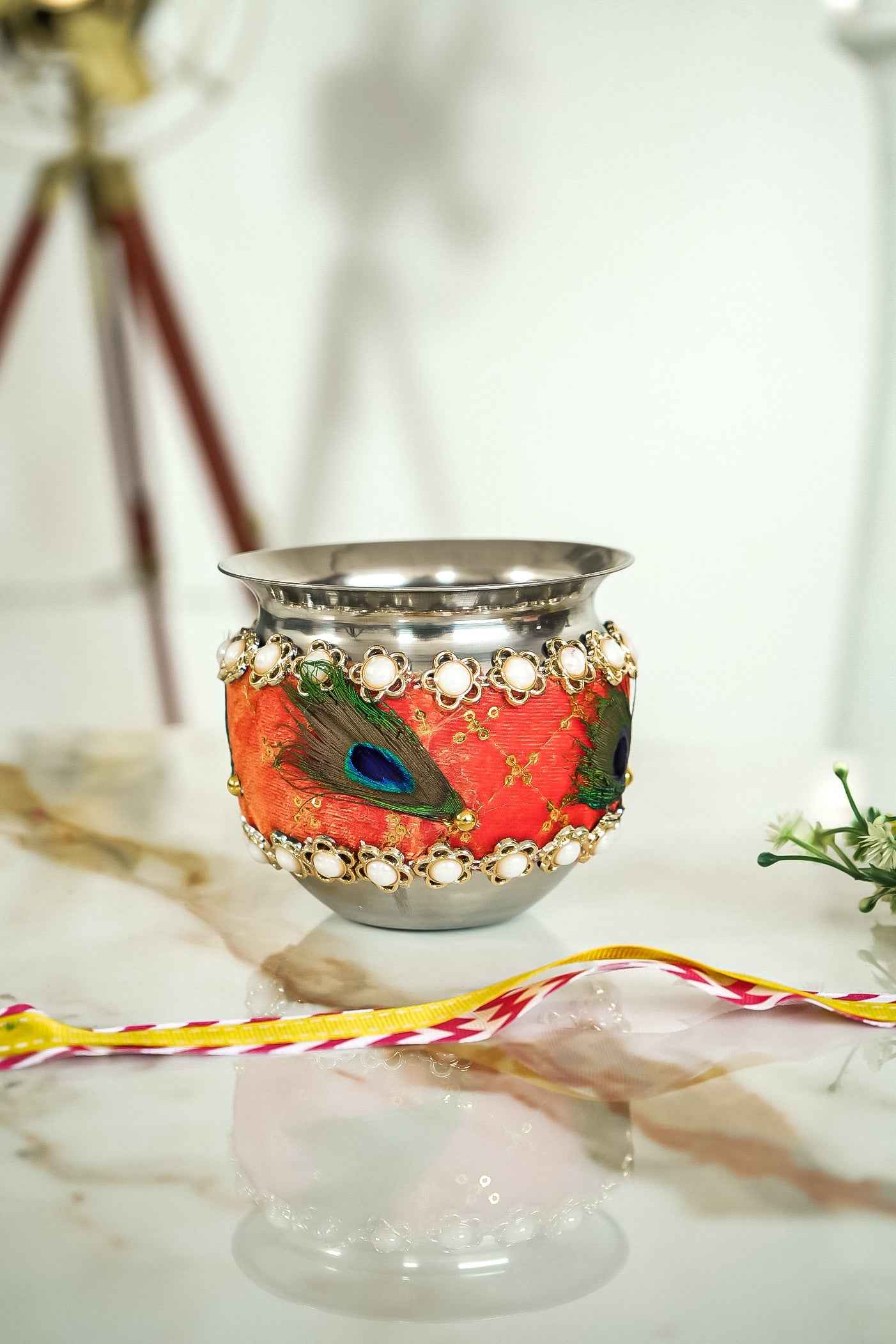 Decorative pot with peacock feather design on a white surface