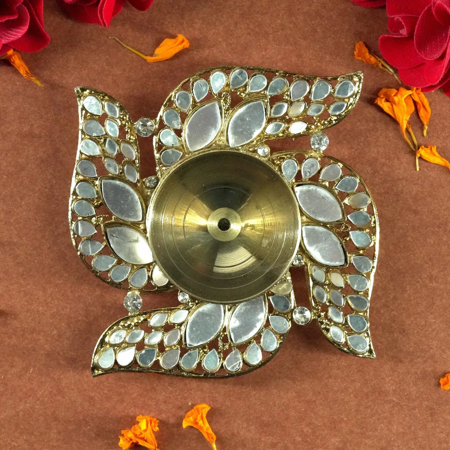 Decorative oil lamp with mirror-like stones on a brown background with flowers.