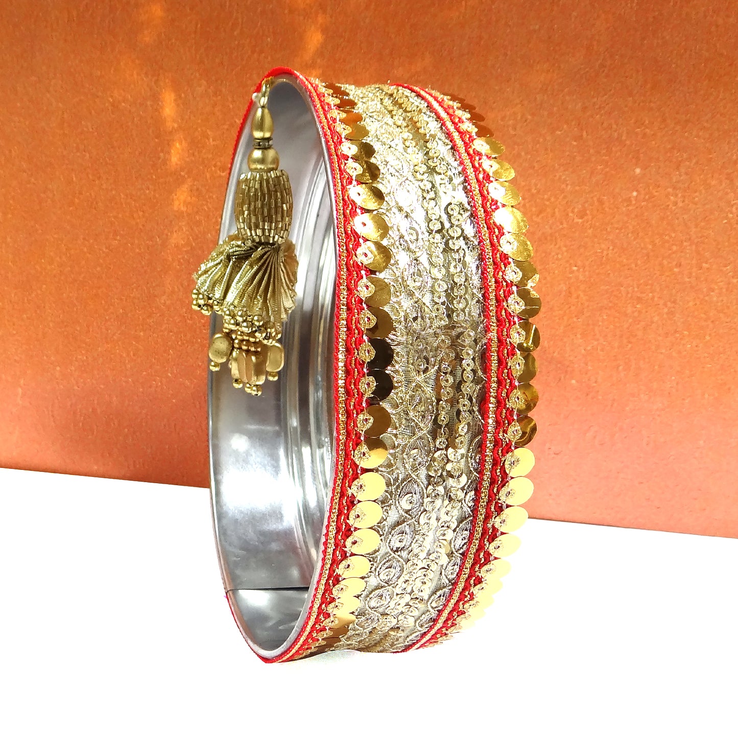 Decorative bangle with gold and red details on an orange background