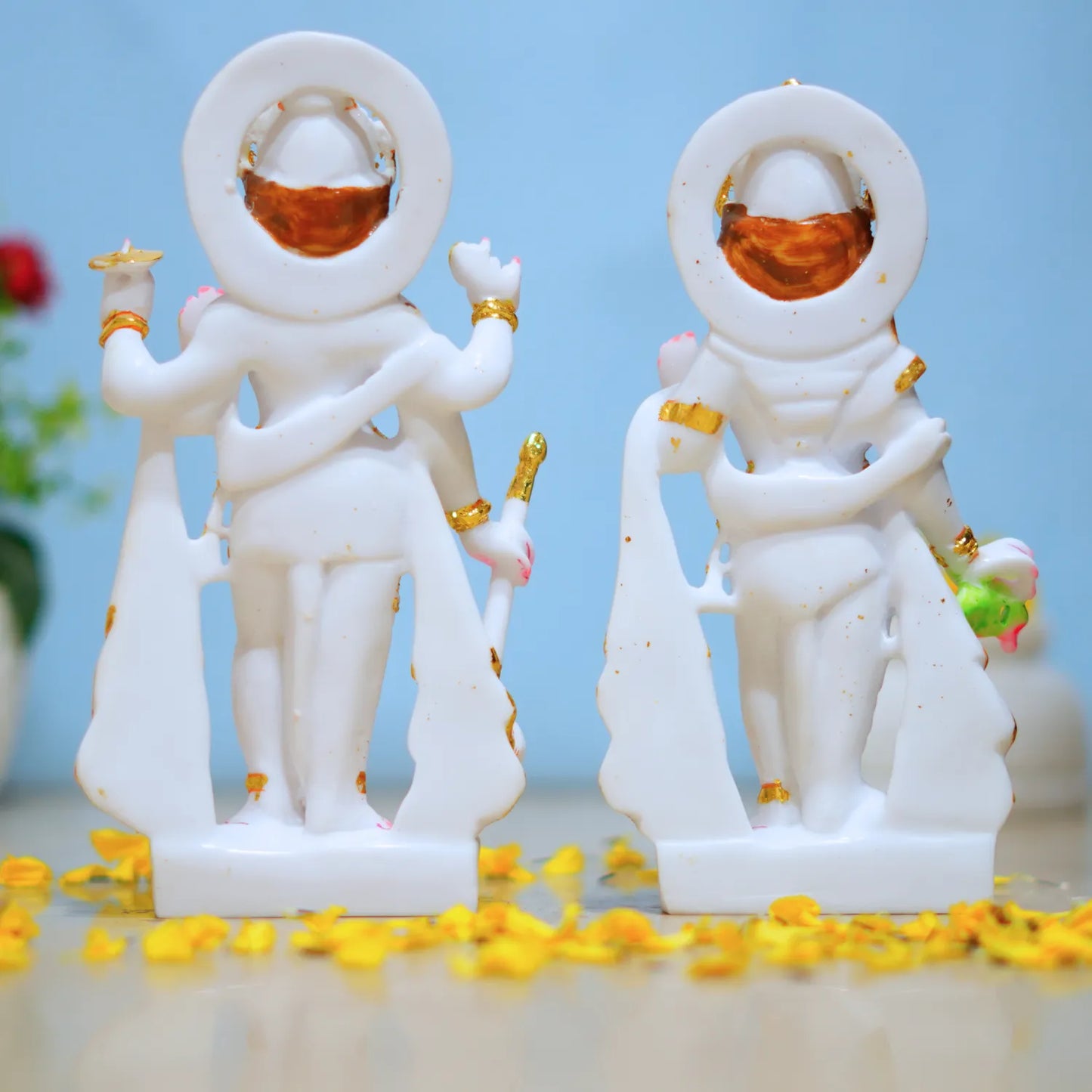 Two white figurines with gold accents on a light blue background
