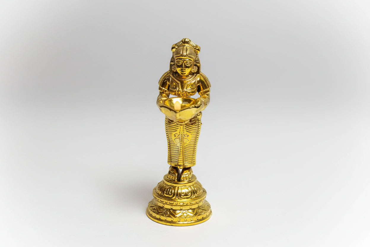 Gold-colored statue of a seated figure on a white background