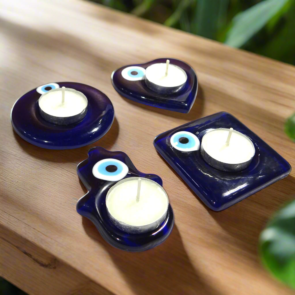Four blue glass candle holders with white candles on a white background