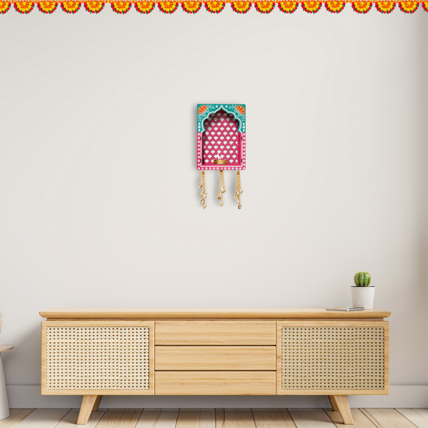 Decorative wall hanging above a wooden cabinet with a plant on a white wall.