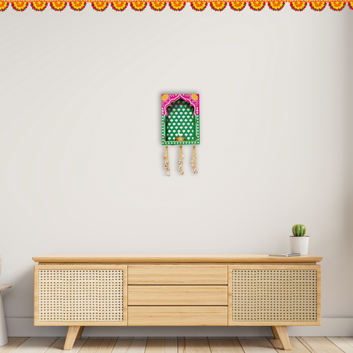 Decorative wall hanging above a wooden cabinet with a small plant on a white wall.