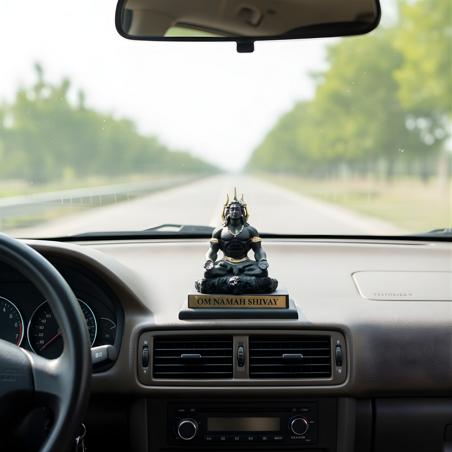 Car dashboard with a Shiva statue ornament and 'OM NAMAH SHIVAY' plaque.