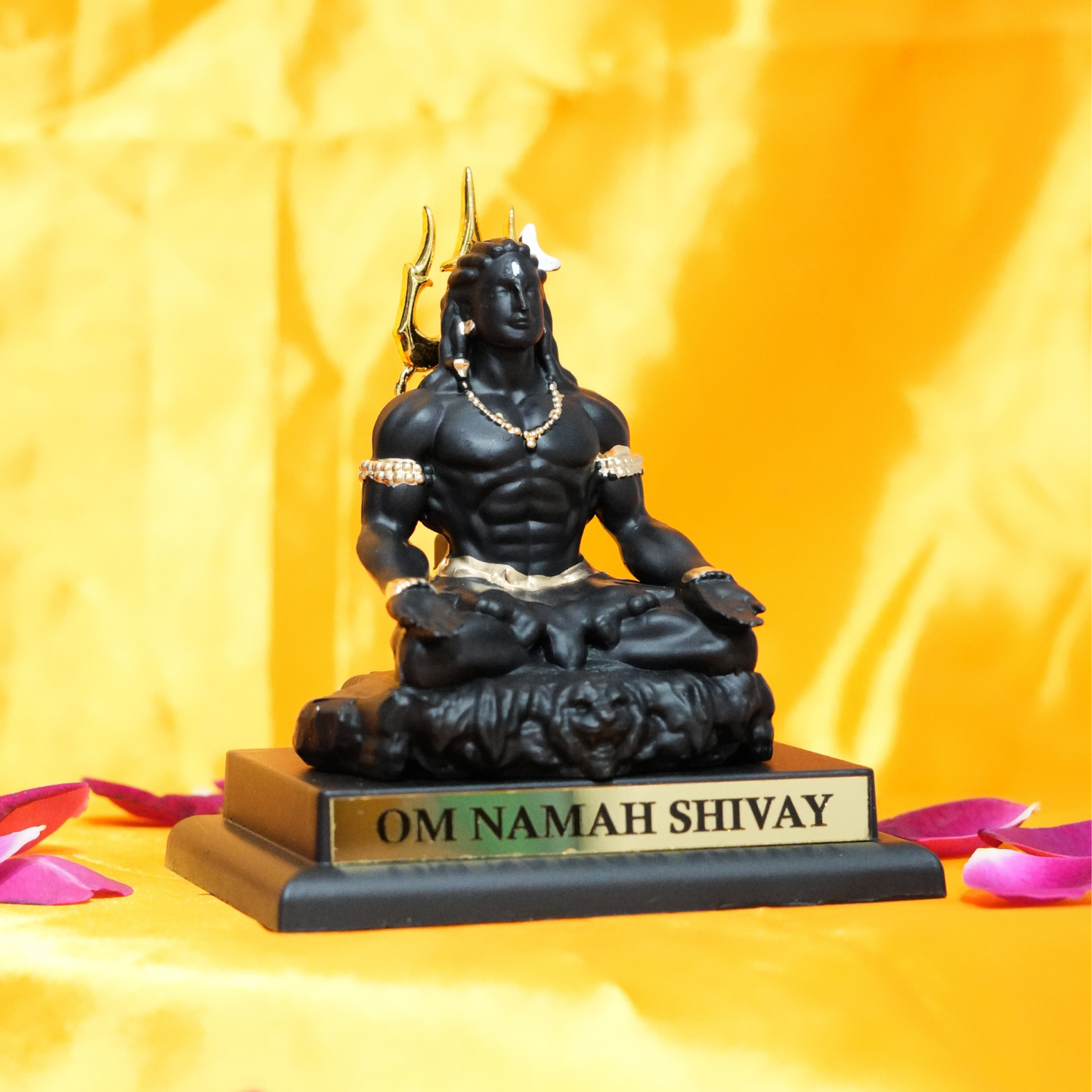 Black statue of a seated figure with 'OM NAMAH SHIVAY' inscription on a yellow background