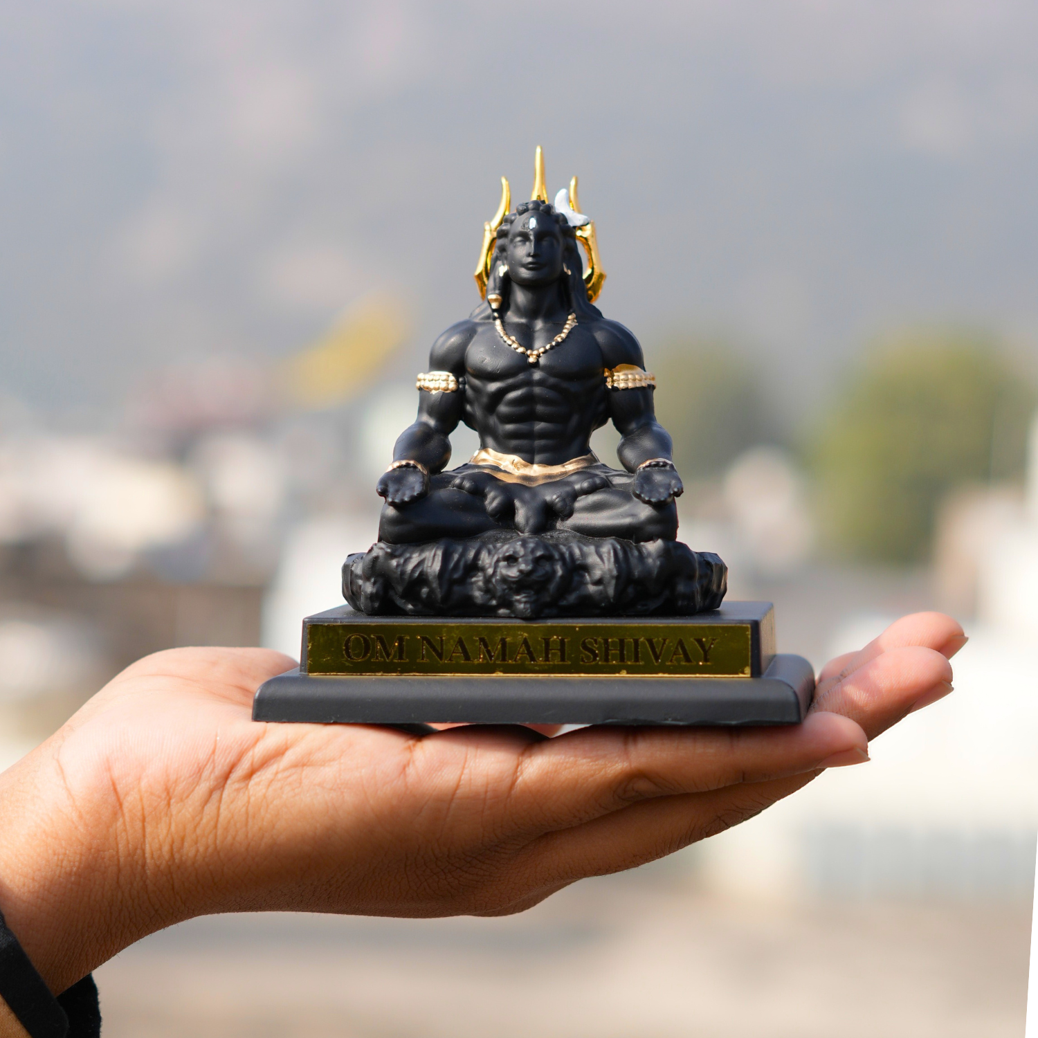 Statue of a muscular figure on a pedestal held in a hand with a blurred background