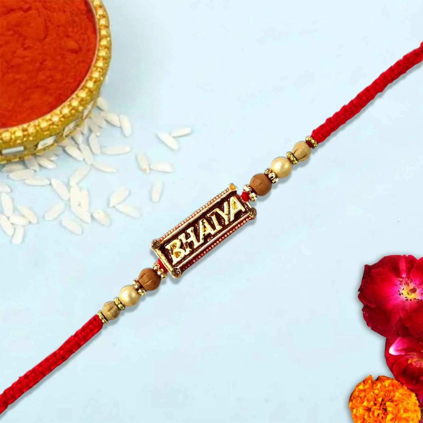 Decorative rakhi with 'Bhaiya' on a light blue background with flowers and rice.