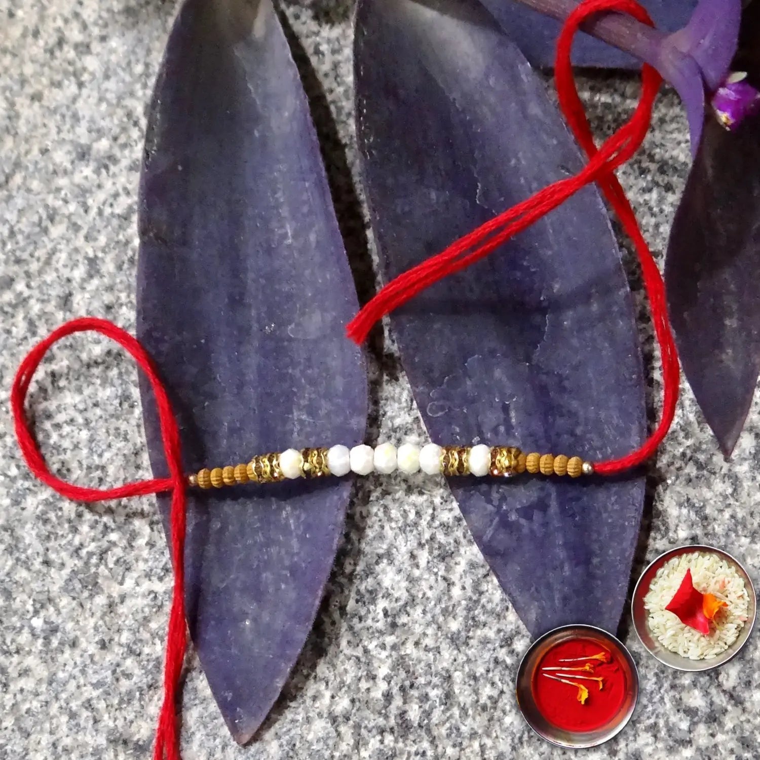Bracelet with red thread on purple sandal, with small bowls of rice and flowers in the background.
