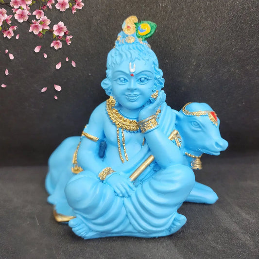 Blue figurine of a deity with gold accents on a dark background