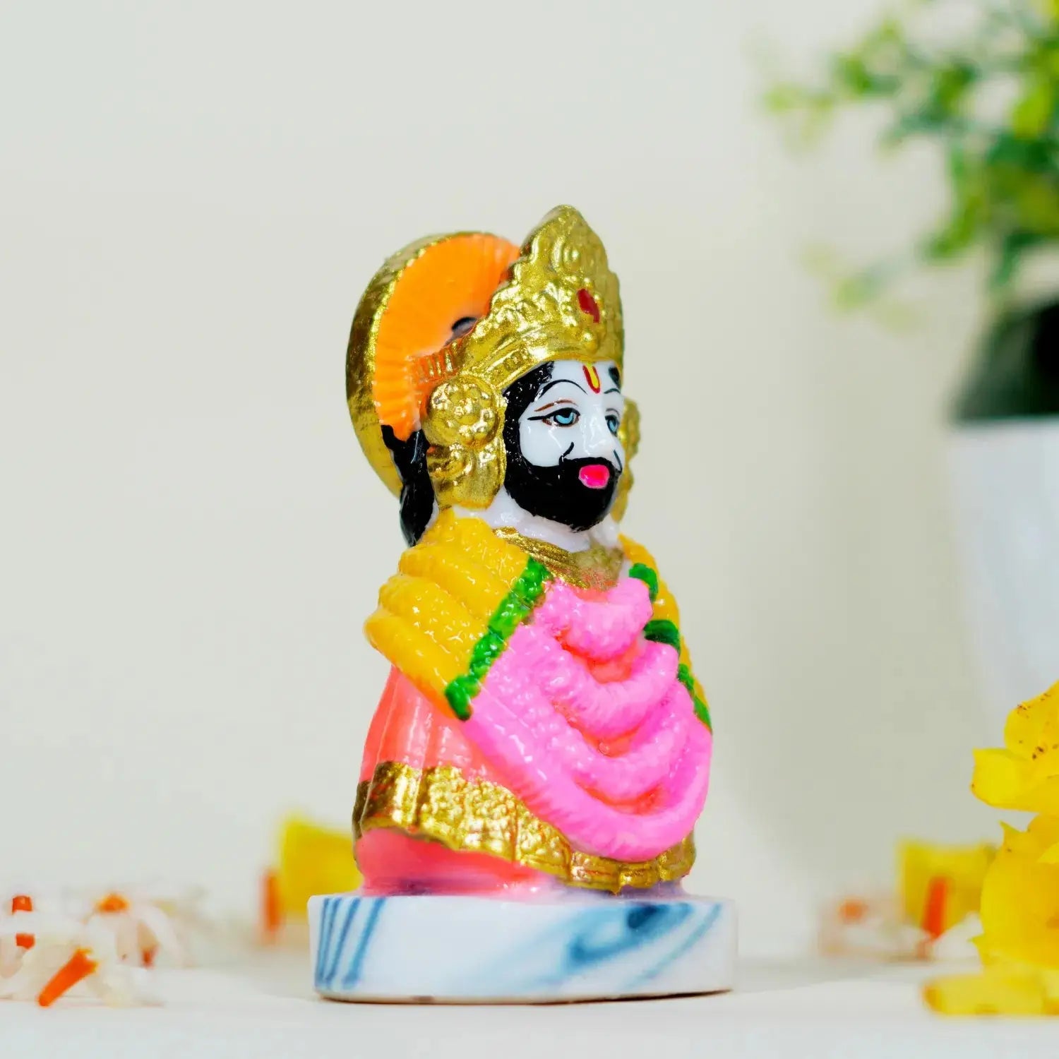 Colorful figurine of a deity on a white surface with a blurred background