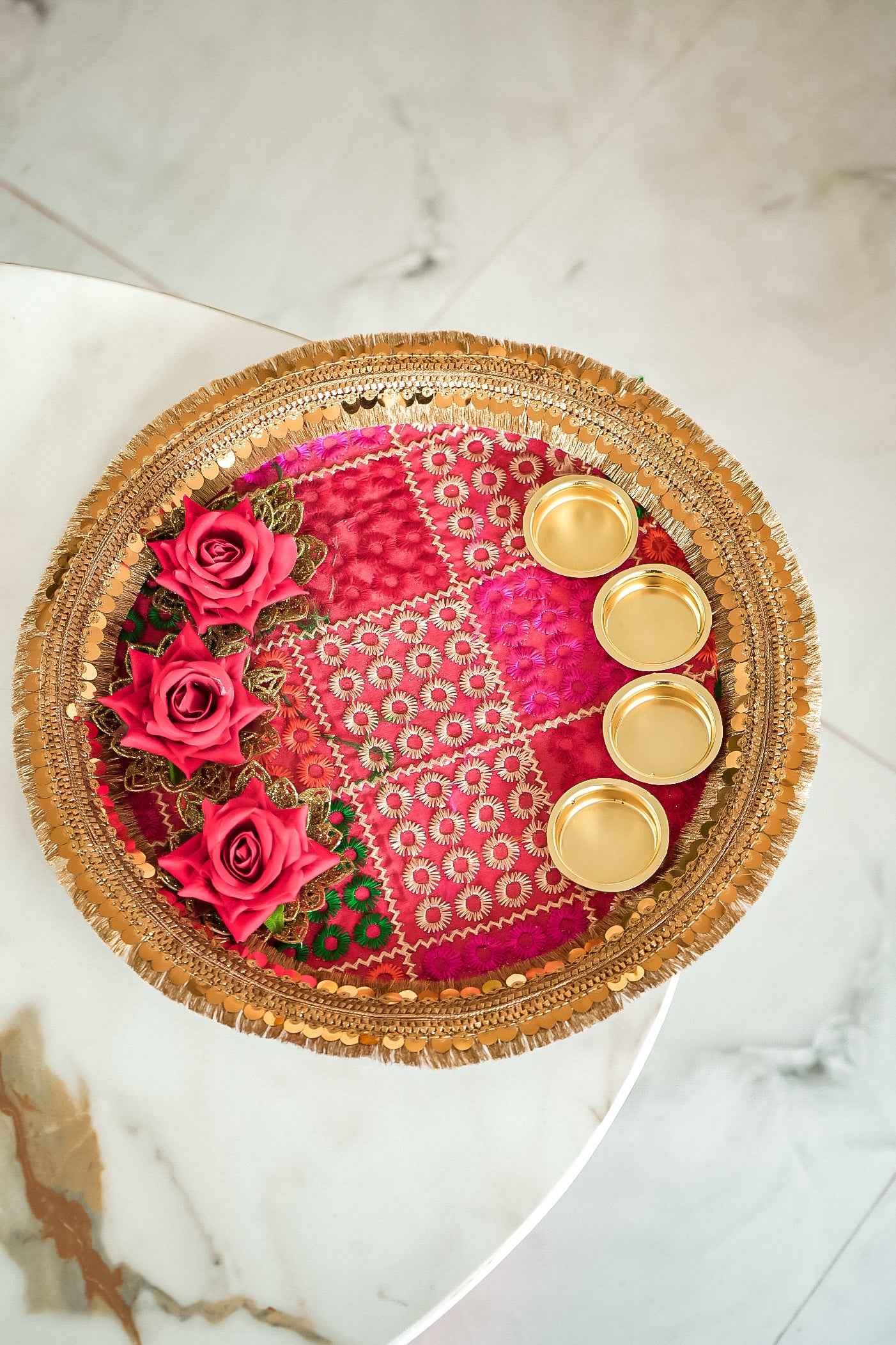 Decorative tray with pink flowers, gold coasters, and a patterned design on a marble surface.