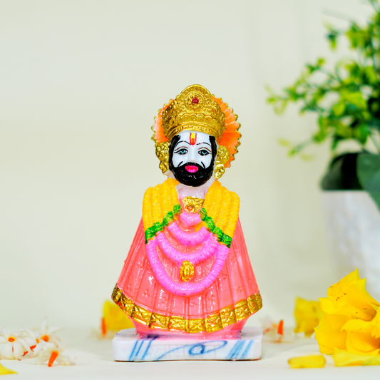 Colorful figurine of a deity with a pink garment and gold crown on a light background