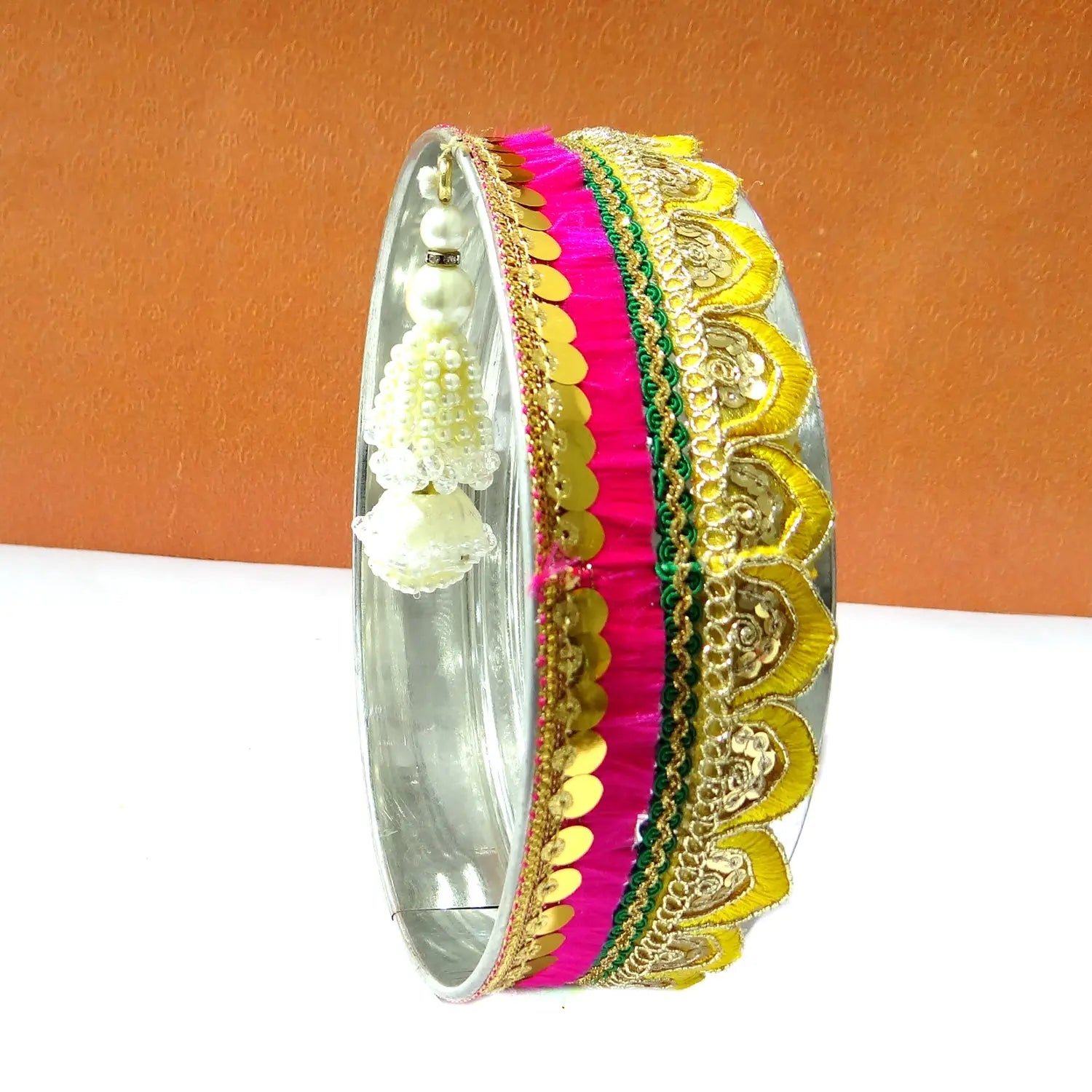 Decorative bangle with colorful patterns on a white surface with an orange background