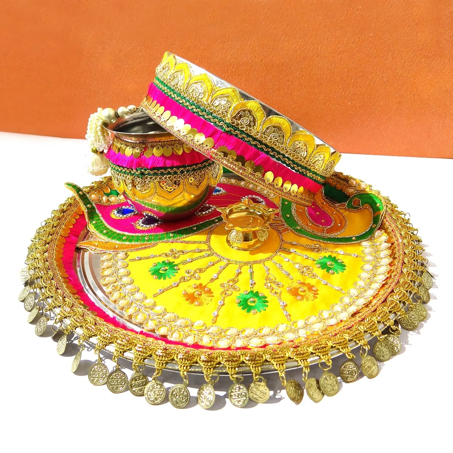Decorative items including a yellow plate with gold accents, a pink and gold lid, and a small golden pot on an orange background.