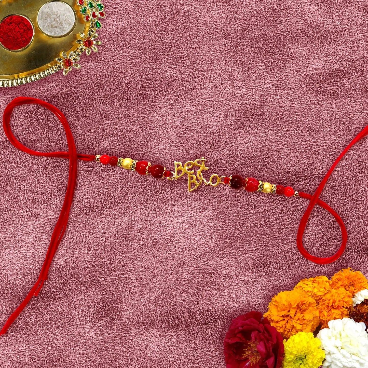 Decorative bracelet with beads and gold letters on a pink background with flowers.