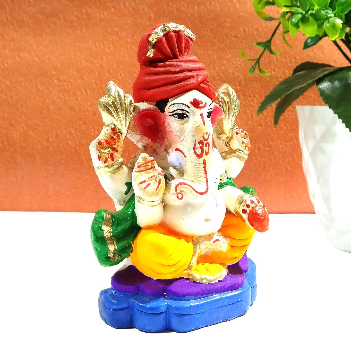 Colorful statue of a deity with a red turban on a white surface.