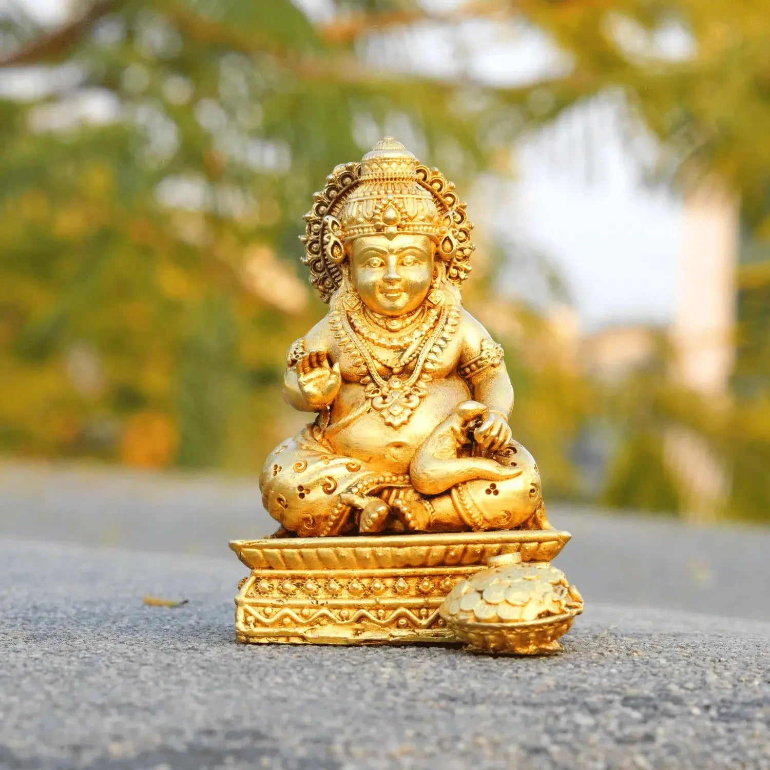 Gold-colored statue of a deity on a blurred natural background