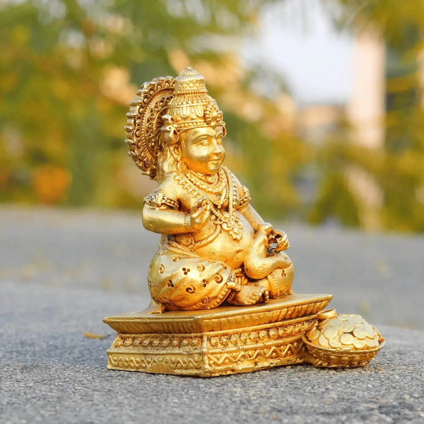 Gold-colored statue of a deity on a blurred natural background