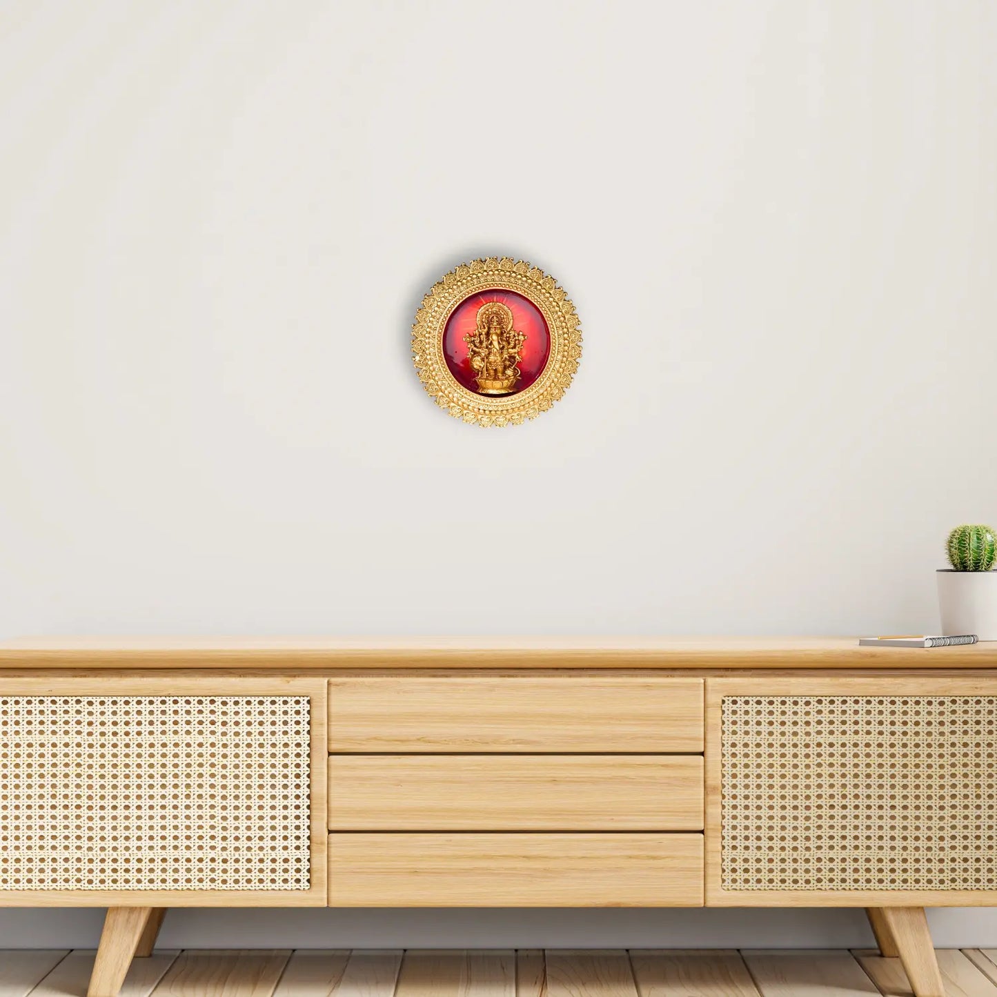 Decorative wall art with a red center and gold frame on a white wall above a wooden cabinet.
