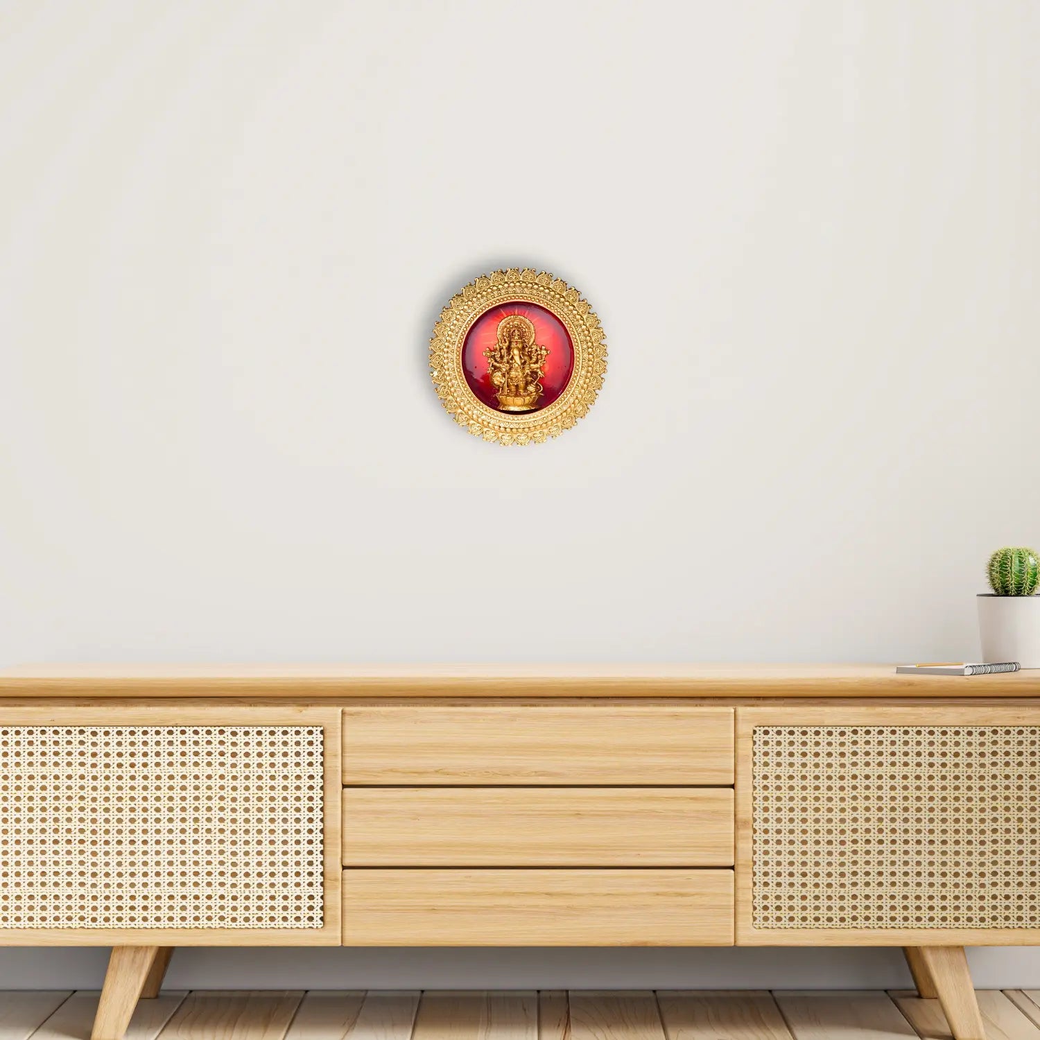 Decorative wall art with a red center and gold frame on a white wall above a wooden cabinet.
