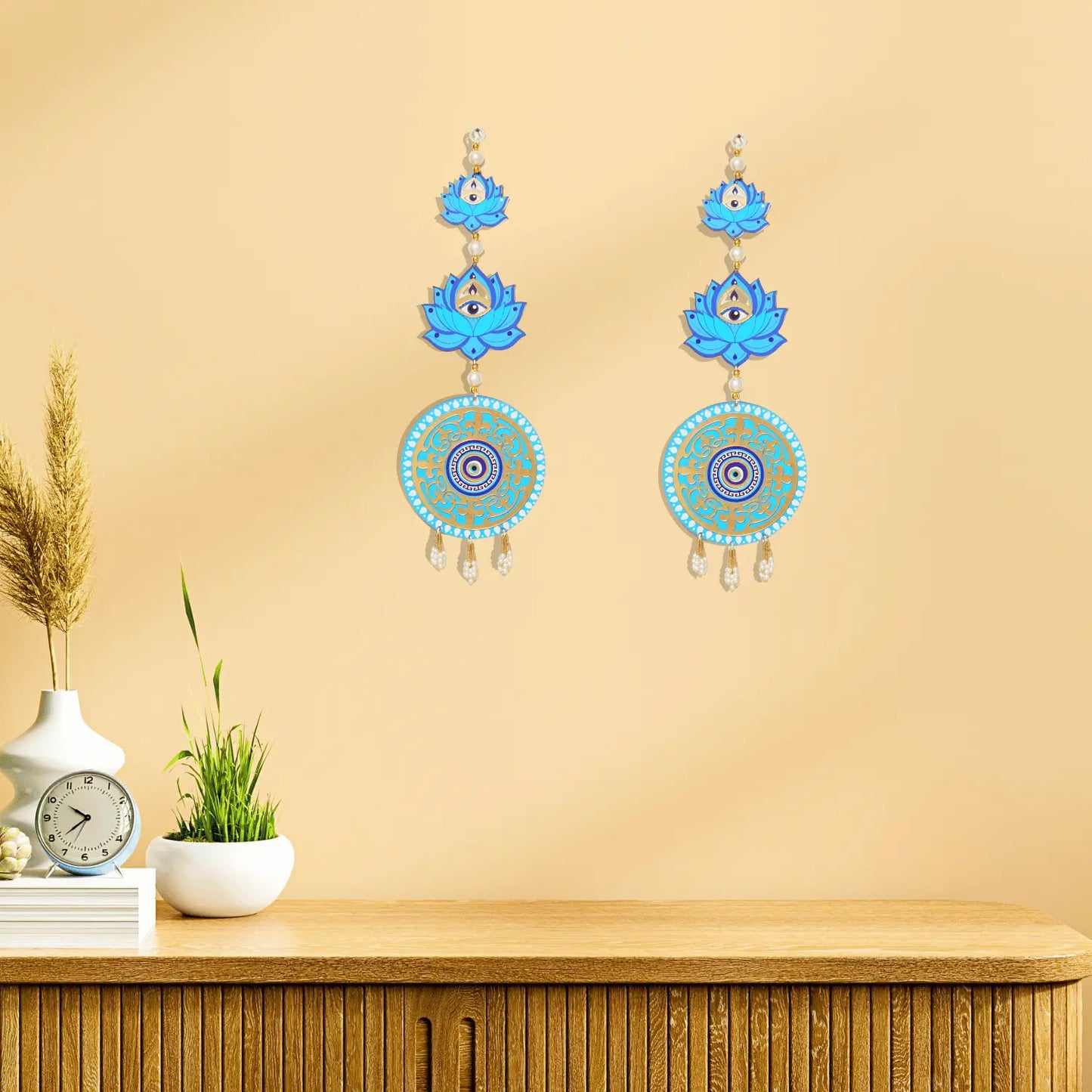 Decorative earrings with blue and gold designs on a beige wall.