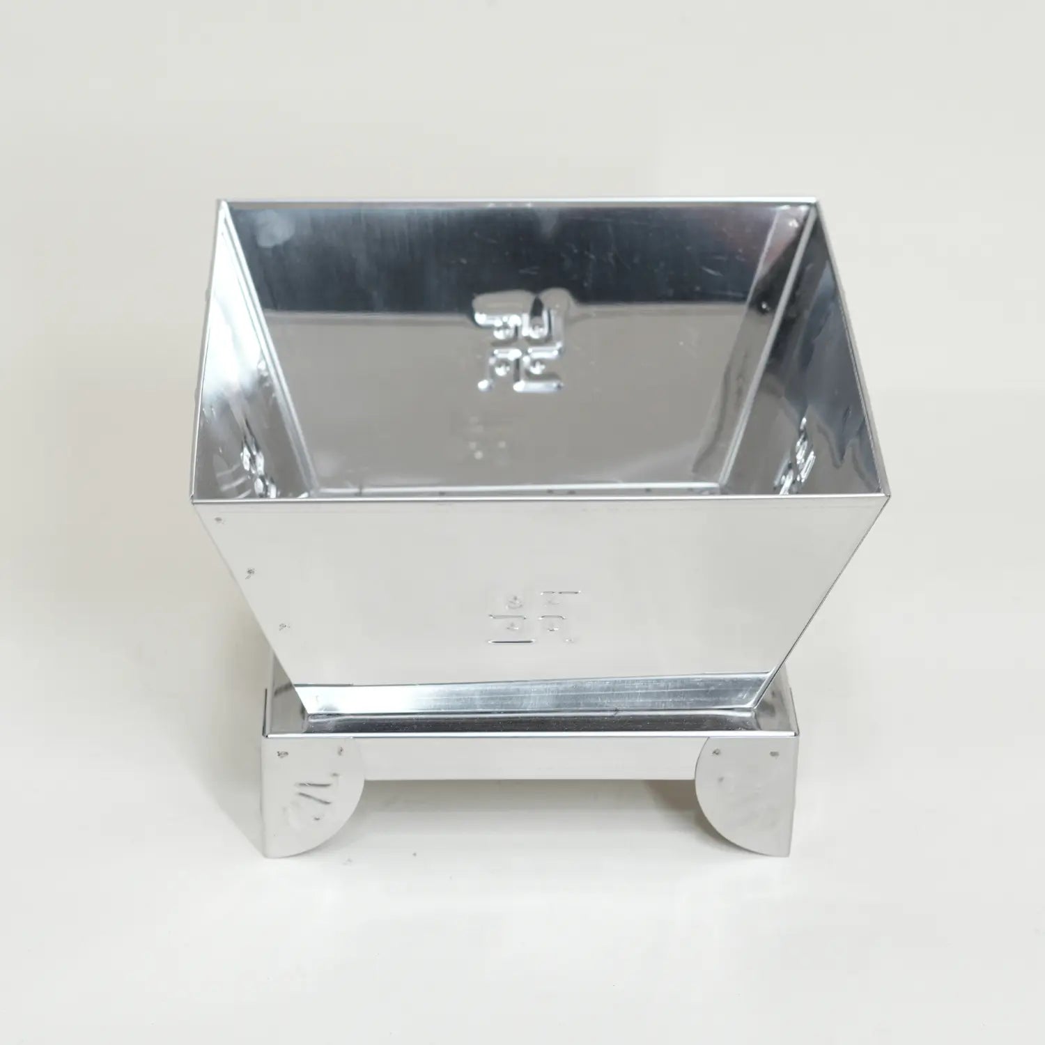 Metallic square container with reflective surface on a white background