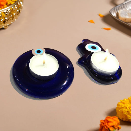 Two blue candle holders with candles on a beige surface with decorative elements.