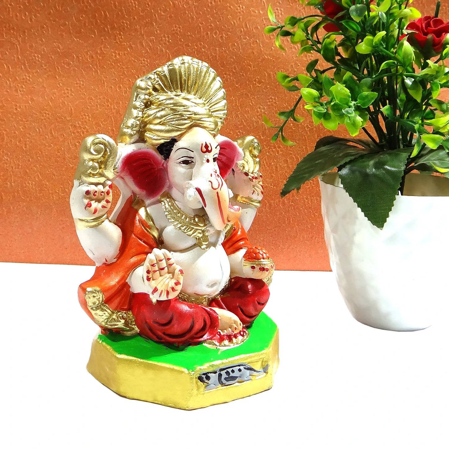 Colorful statue of a deity with a plant on an orange background