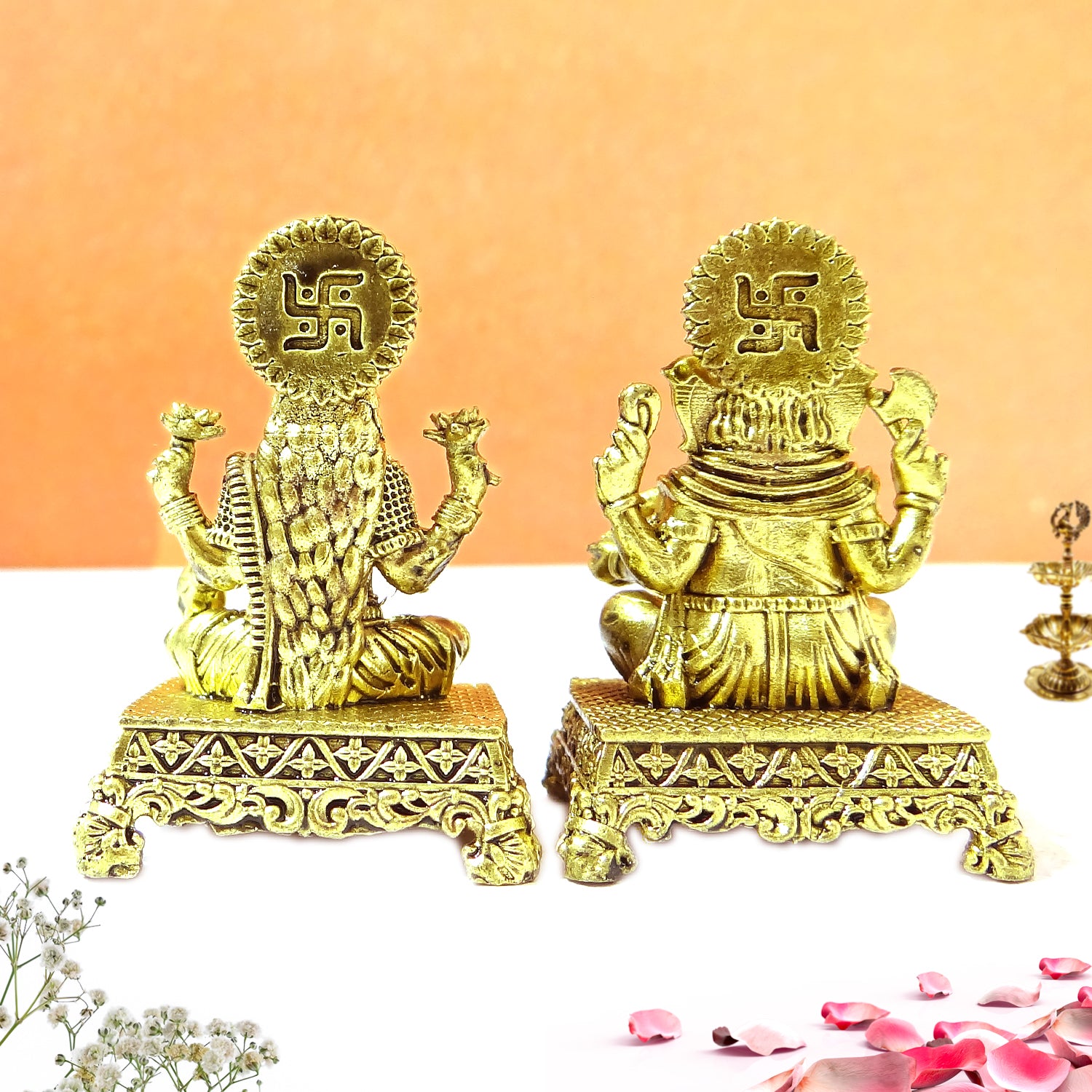 Two gold-colored statues with a swastika symbol on an orange background