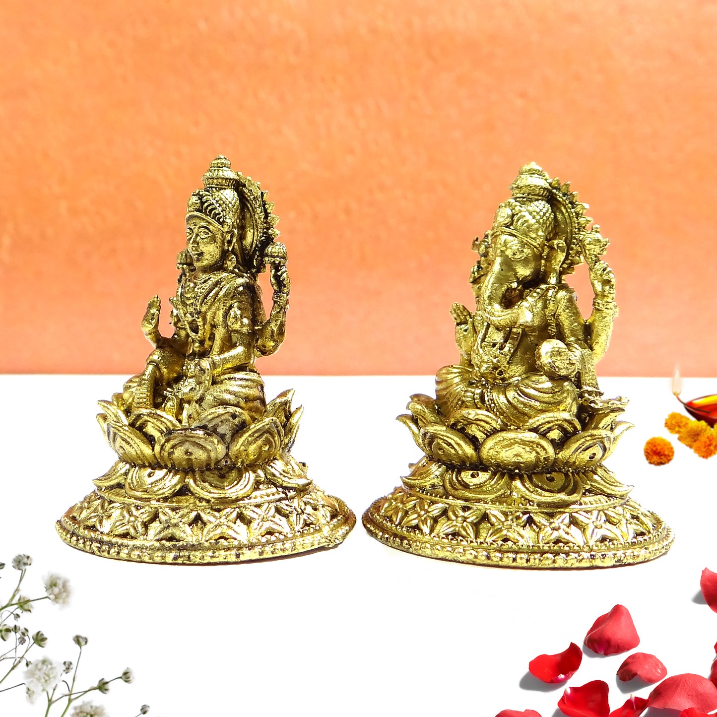 Two gold-colored statues on a white surface with a peach background