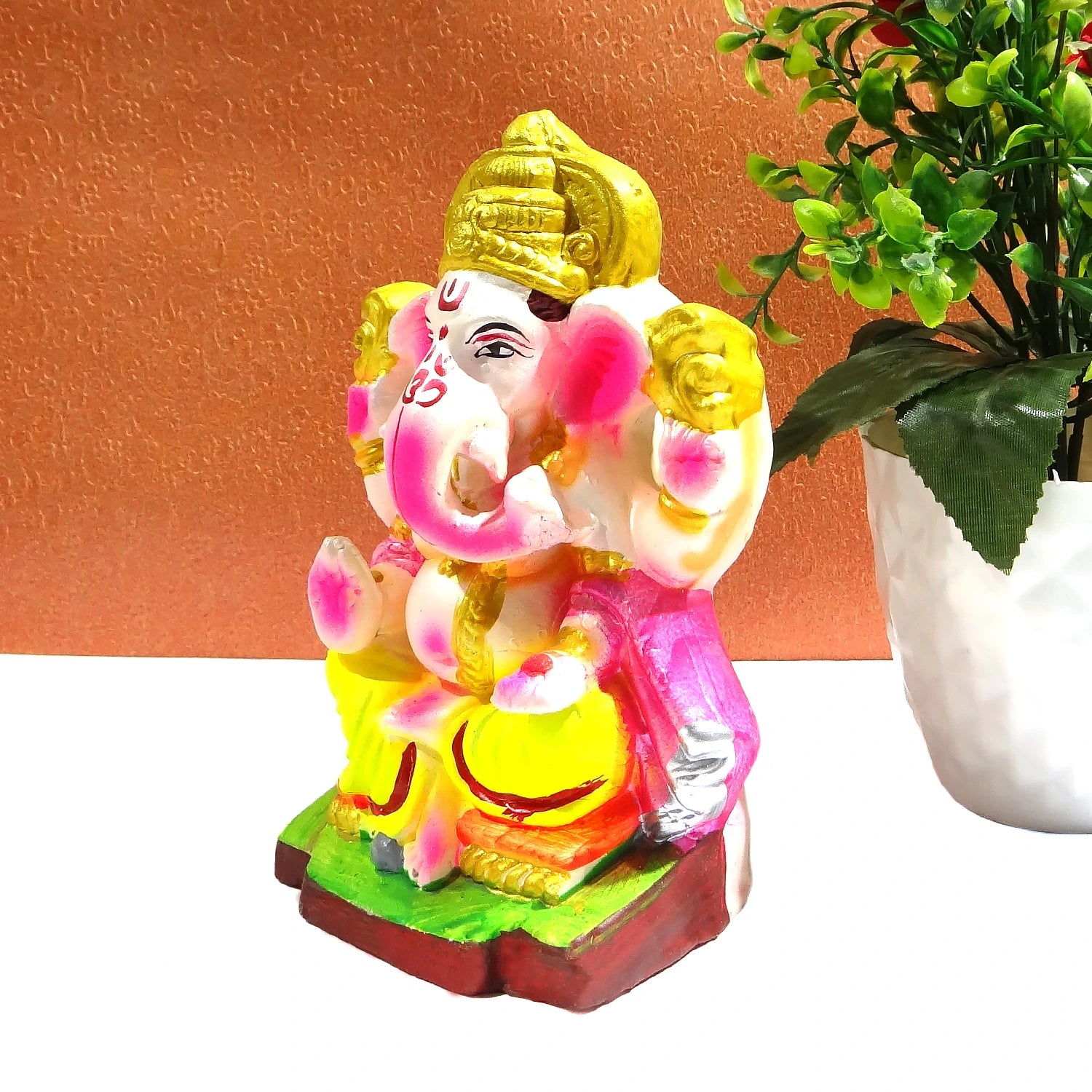 Colorful statue of a deity with a plant in the background