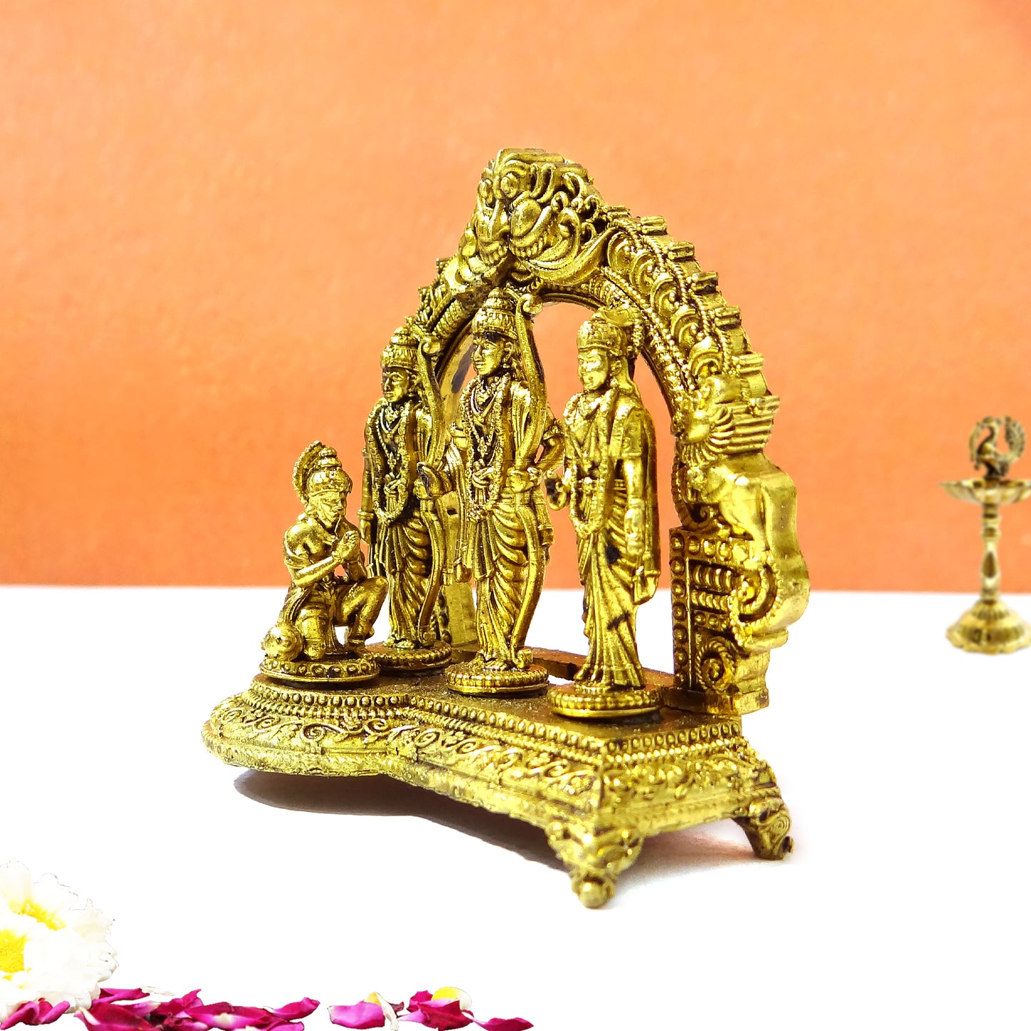 Decorative gold statue with intricate designs on a white surface with an orange background