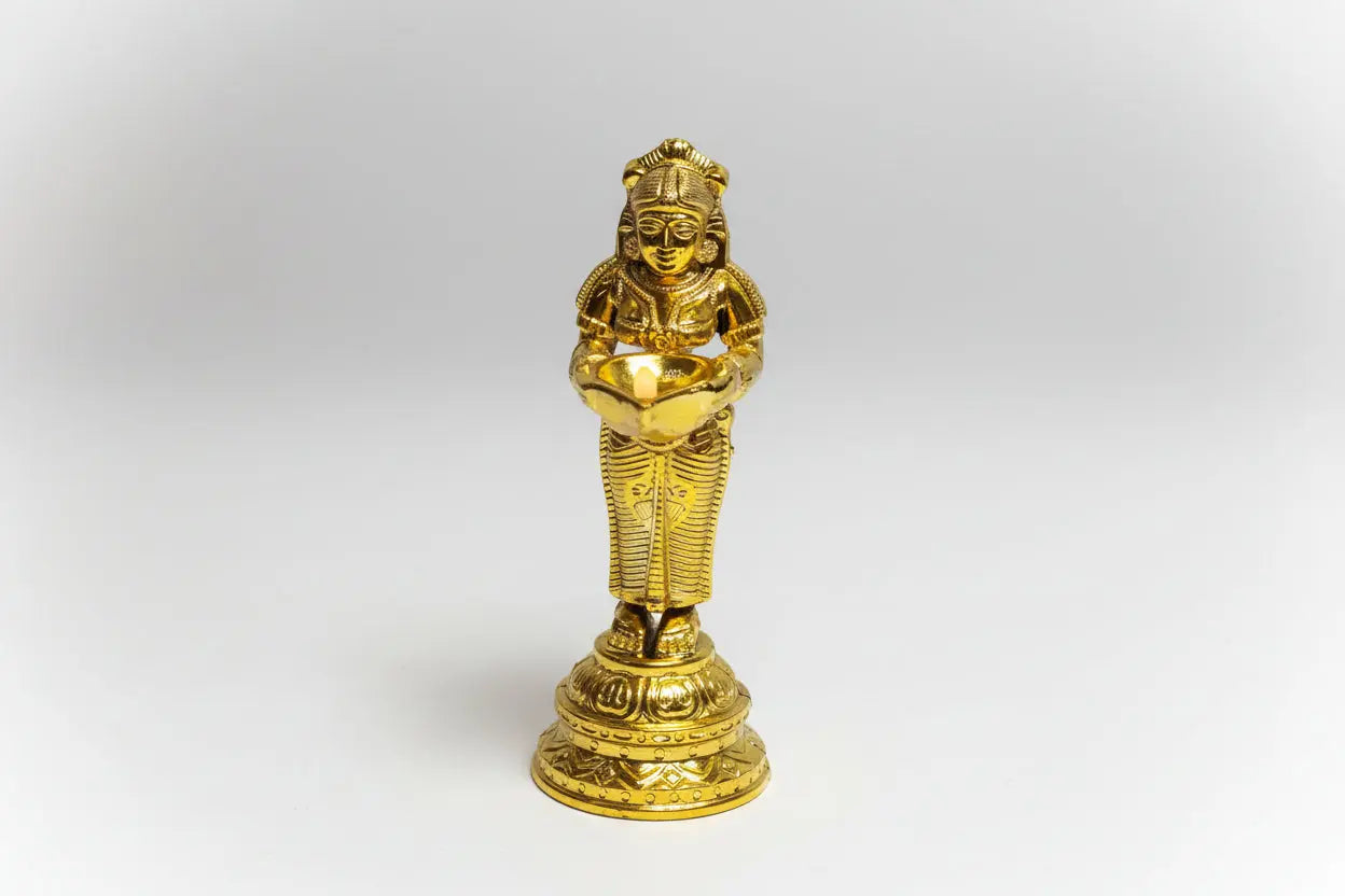 Gold-colored statue of a seated figure on a white background