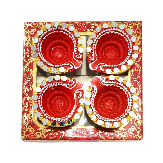 Four red Diwali diya candles in a decorative box with gold and white patterns on a white background.
