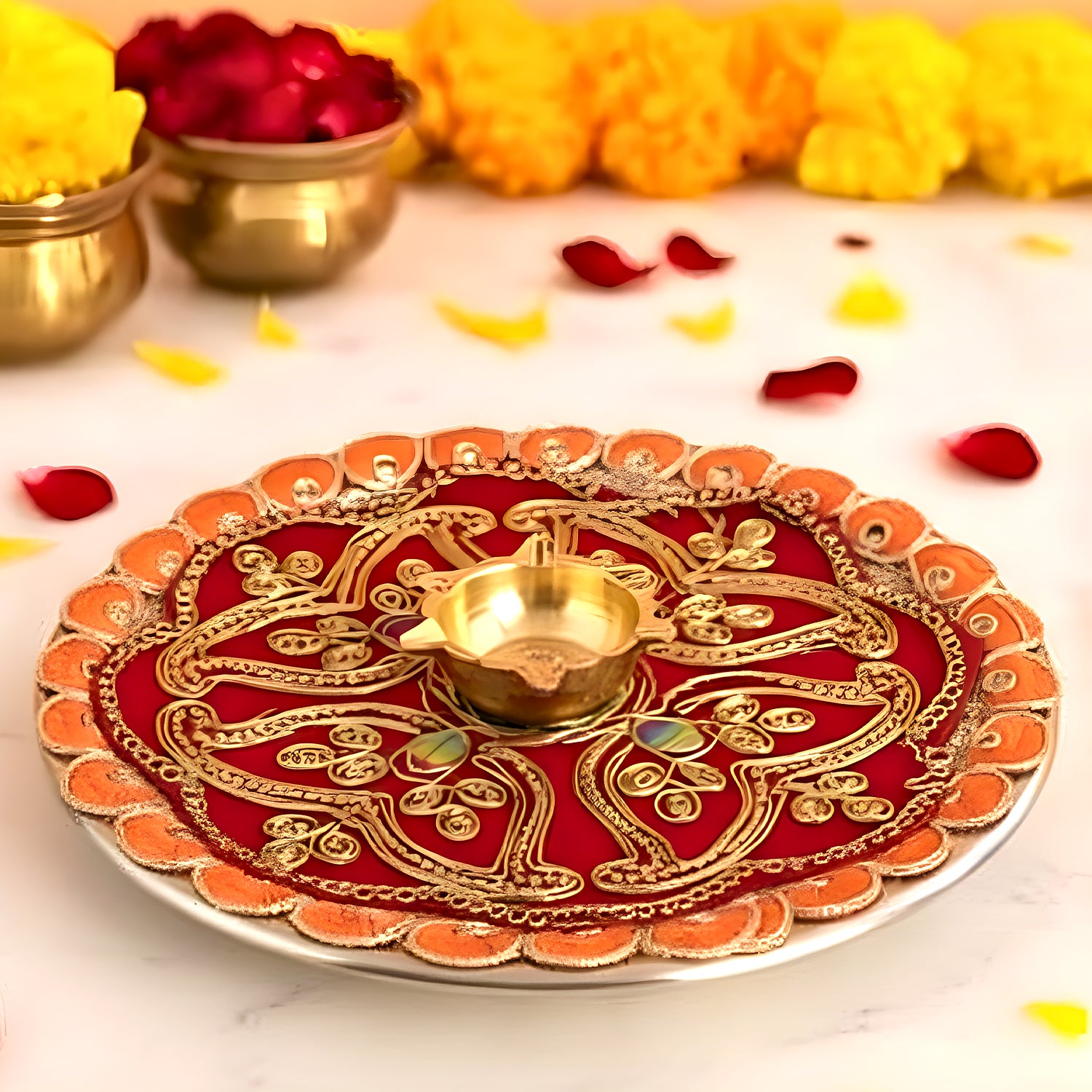 Decorative red and gold plate with a lit candle on a marble surface with candles and flowers.