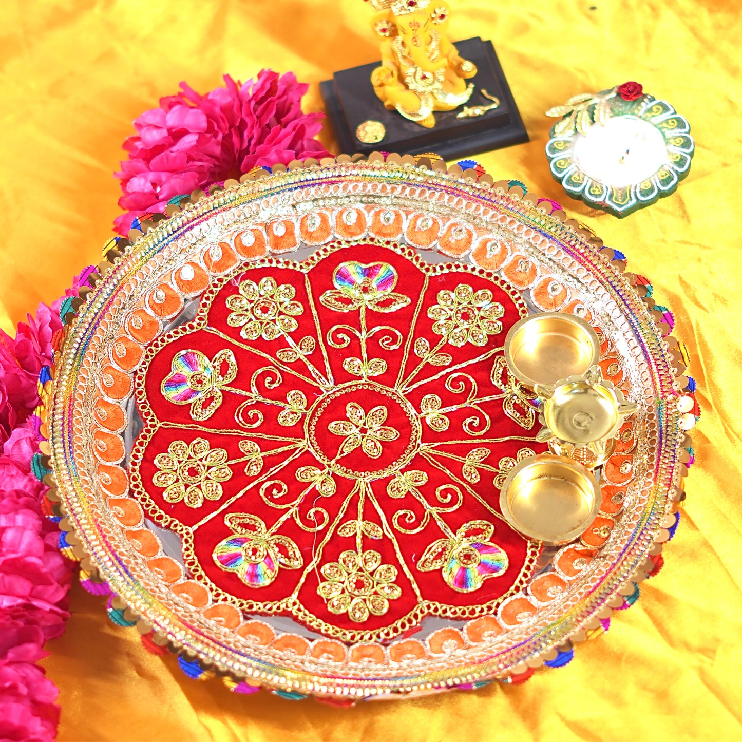 Decorative red plate with gold patterns on a yellow fabric. Decorative Pooja Thali 12 Inch for Festivals & Gifting By Upharkarobackground
