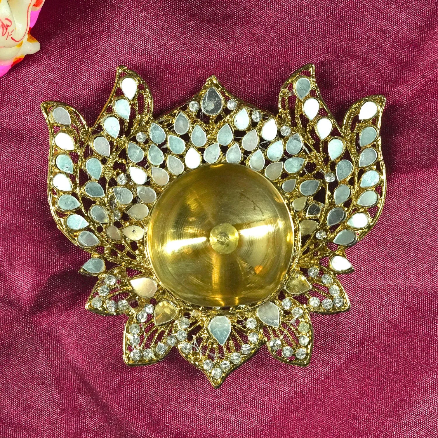 Decorative gold brooch with mirror-like stones on a pink fabric background