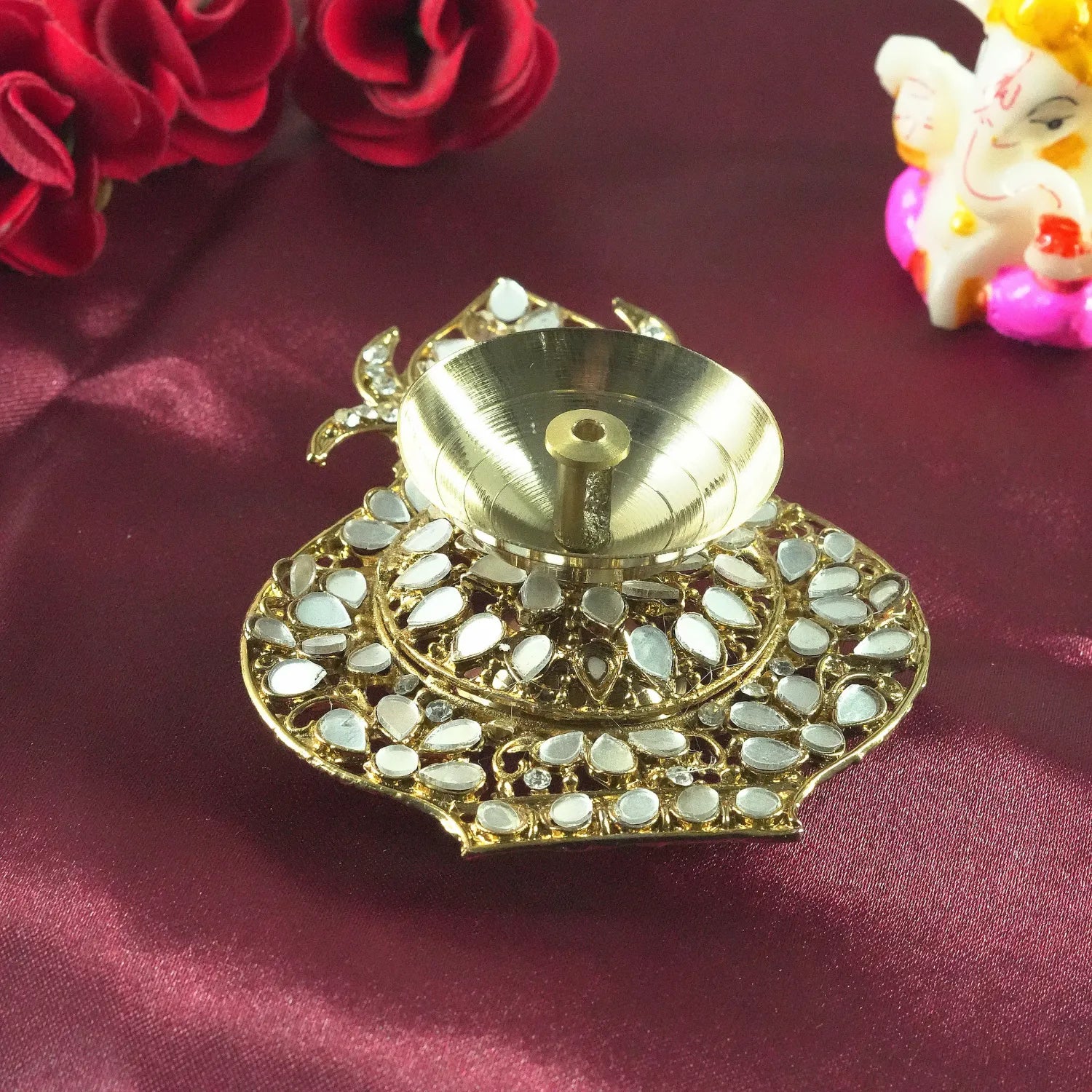 Decorative gold lamp with gemstones on a maroon fabric background