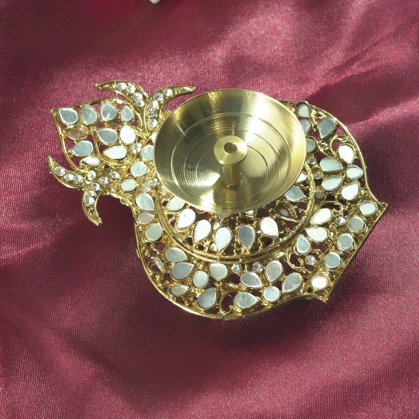 Decorative gold lamp with mirror-like stones on a maroon fabric background