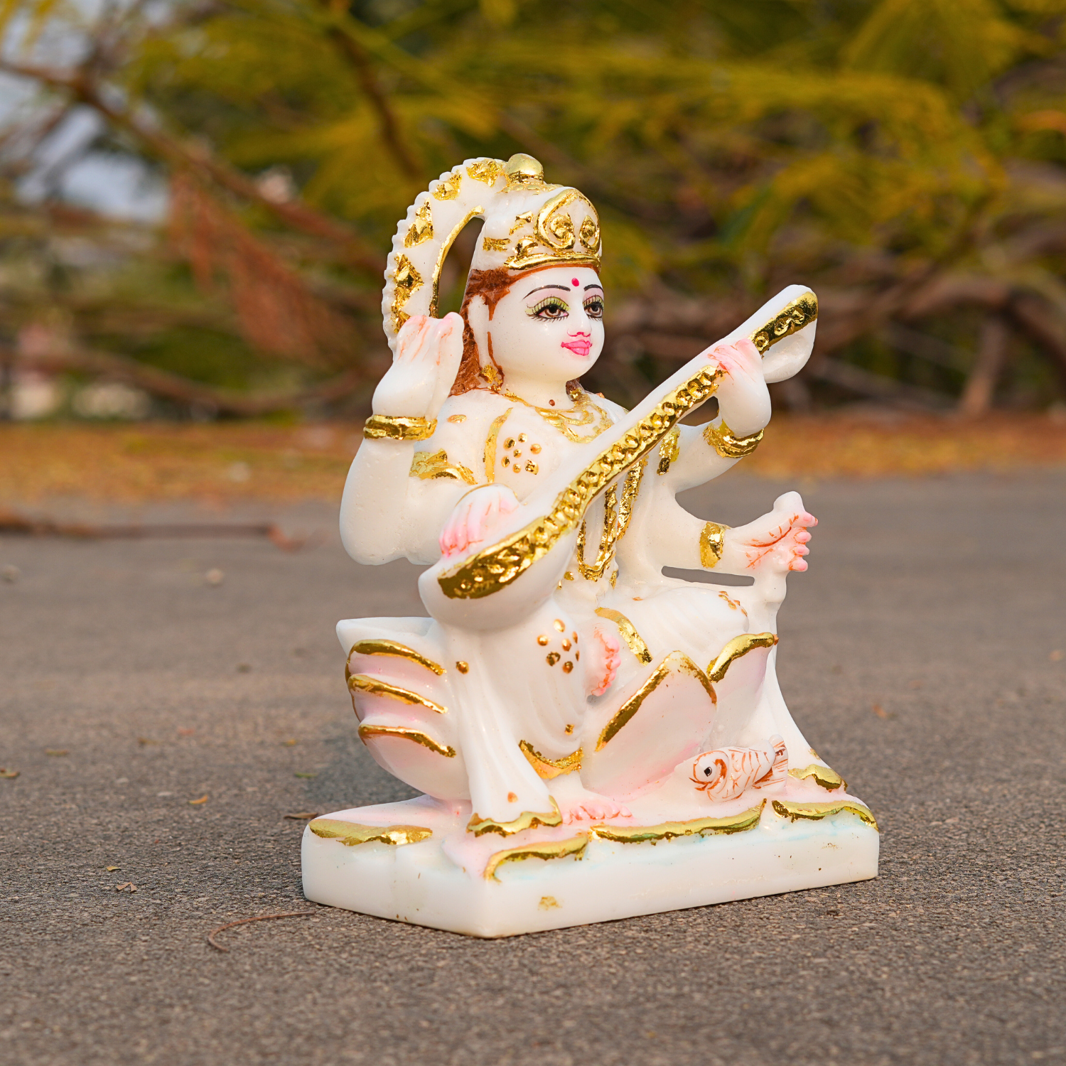 Decorative statue of a deity with gold and pink details on a textured surface.
