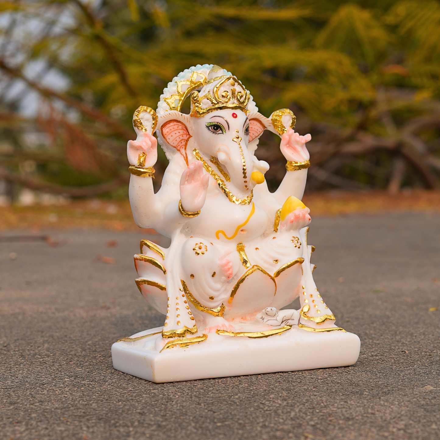 Decorative statue of a deity with gold and white details on a blurred natural background