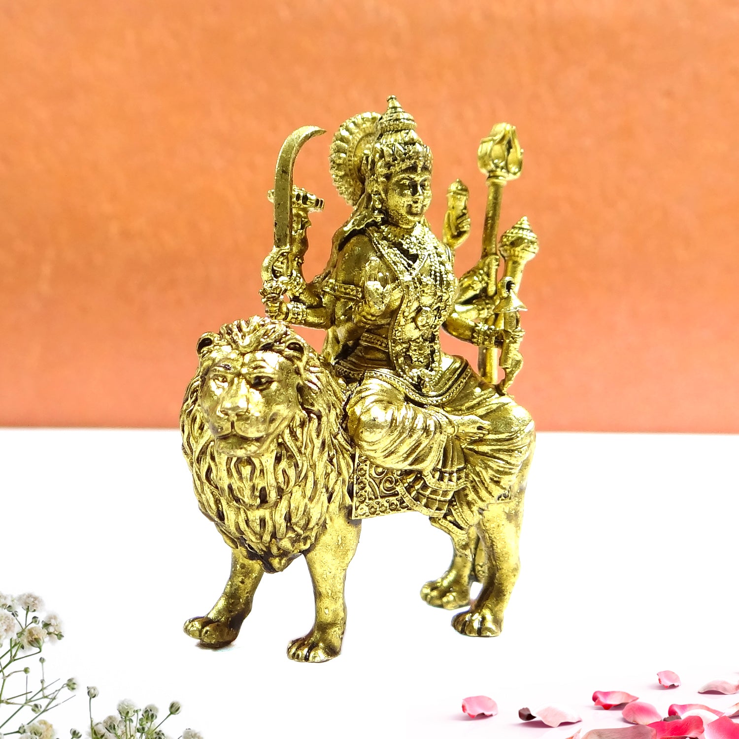 Gold statue of a deity sitting on a lion against an orange background