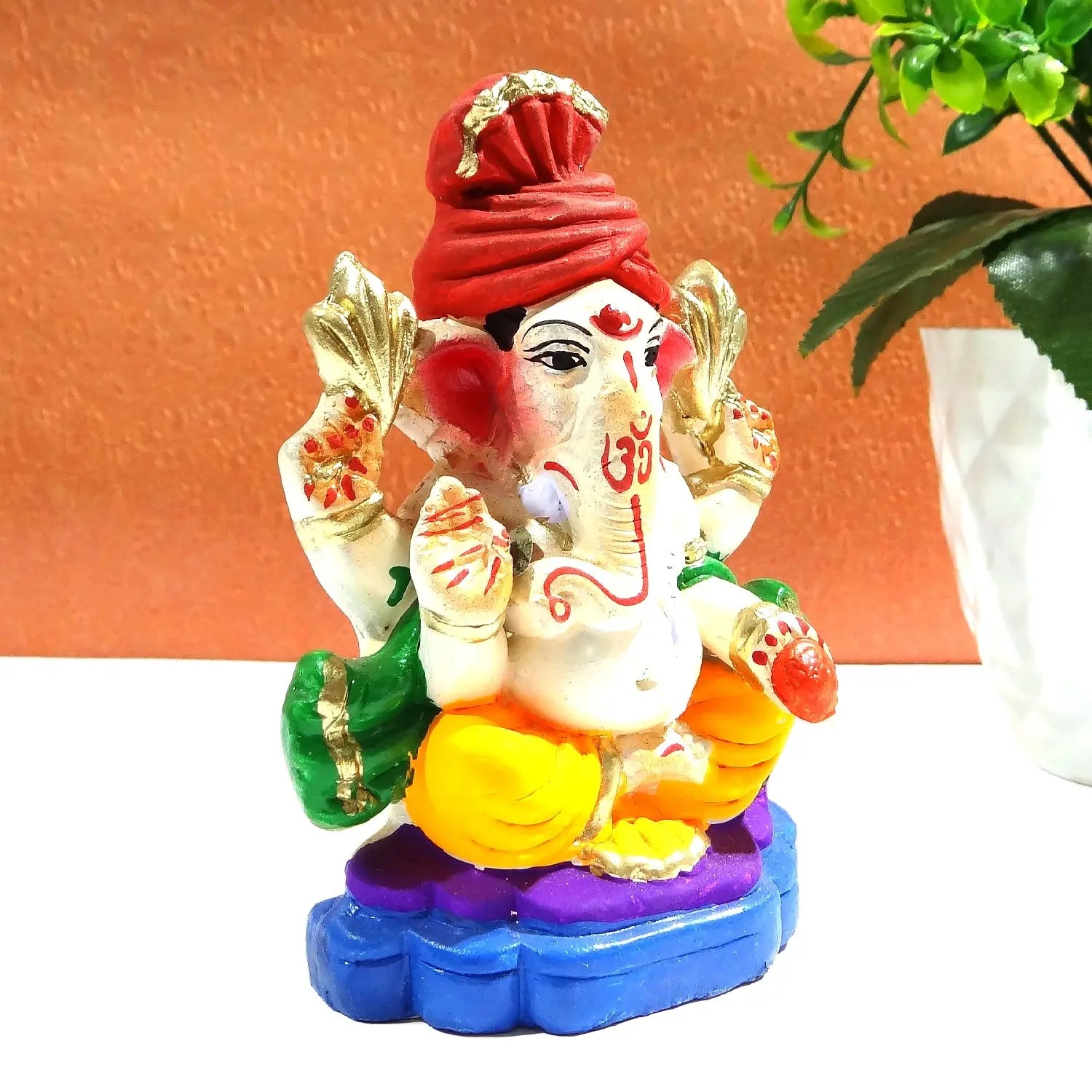 Colorful statue of a deity with a red turban on a white surface.