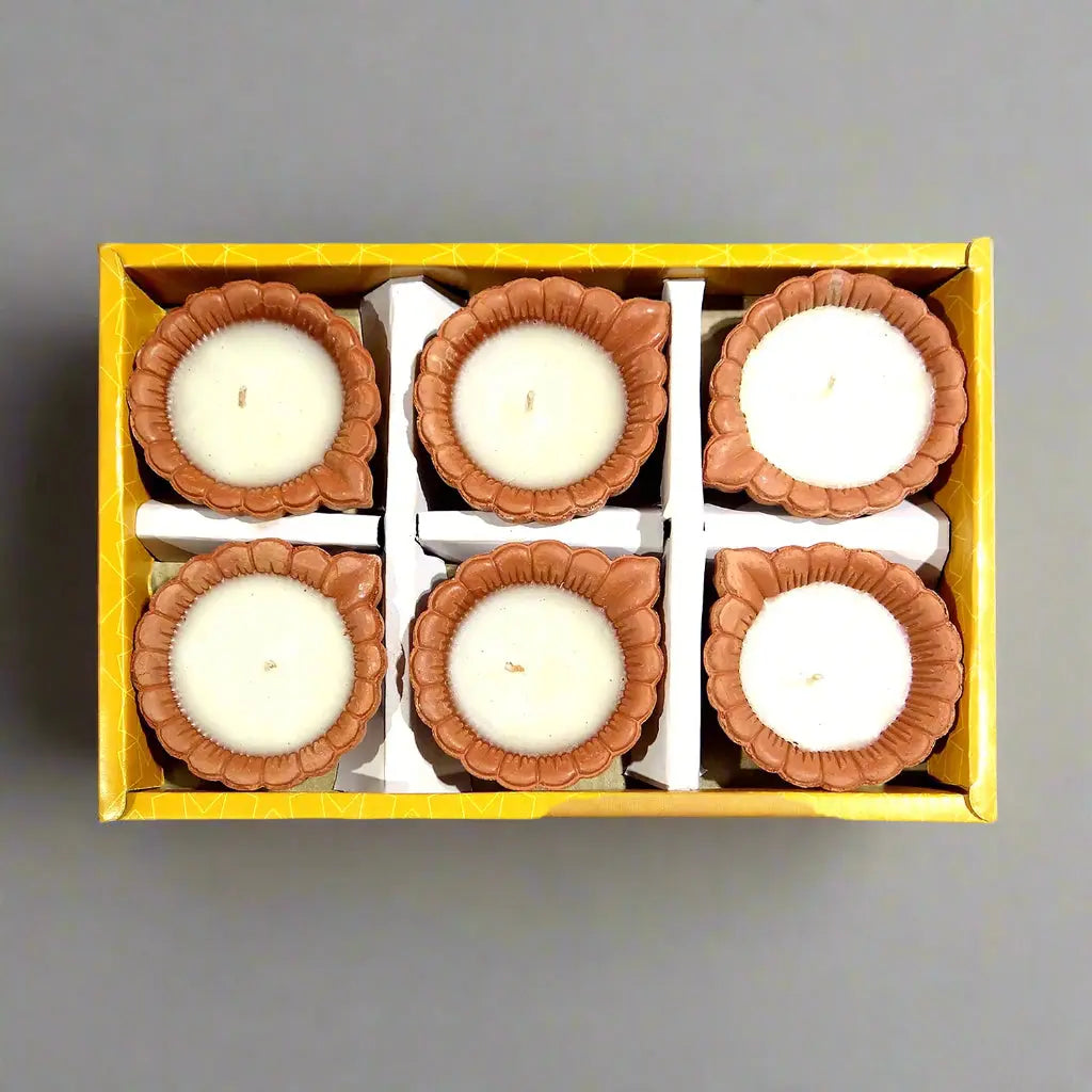 Set of six small candles in decorative holders in a yellow box on a white background
