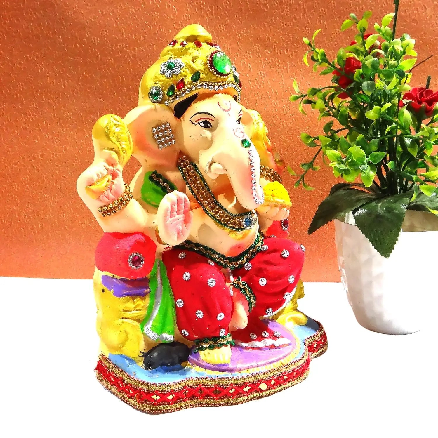 Colorful statue of a deity with a plant on an orange background