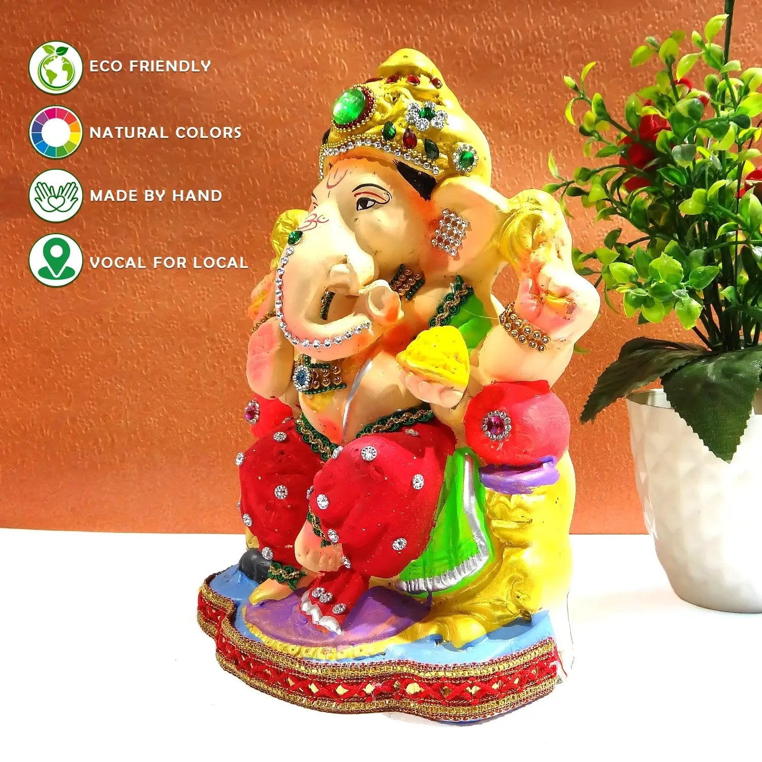 Colorful Ganesh statue with decorative elements on a white surface against an orange background