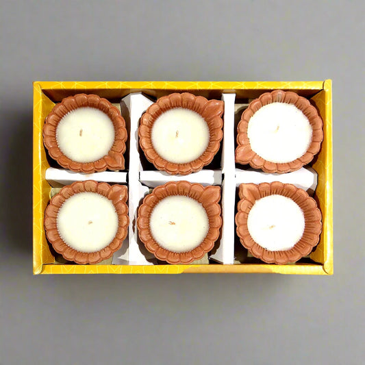 Set of six small candles in decorative holders in a yellow box on a white background