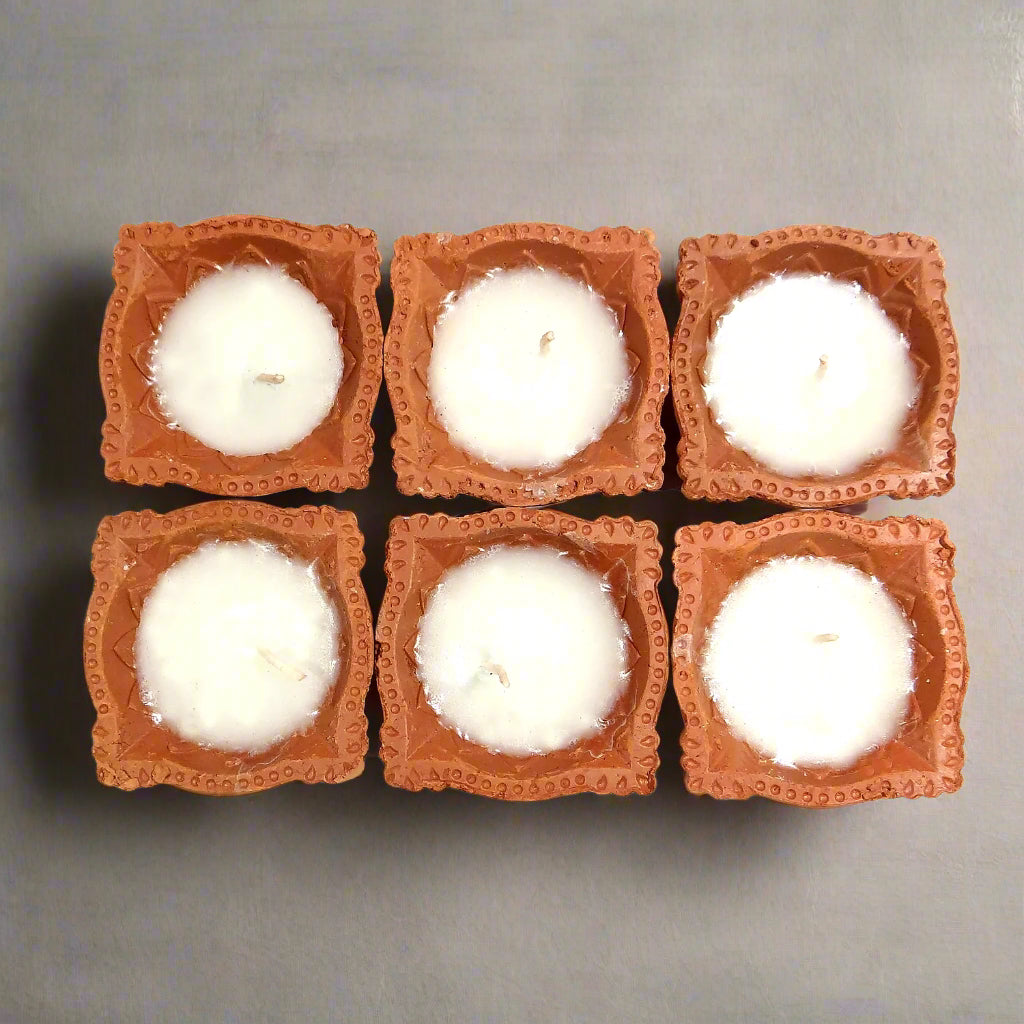 Six square candles with terracotta holders on a white background
