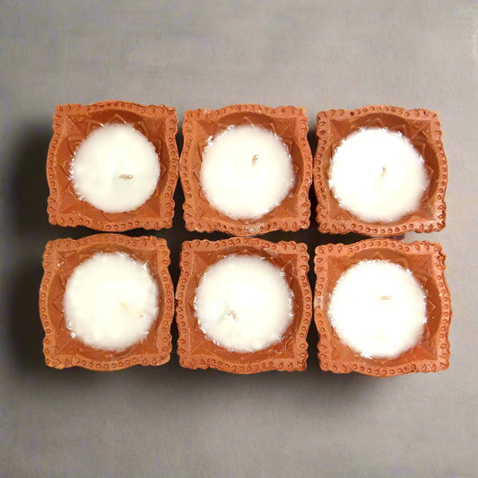 Six square candles with terracotta holders on a white background